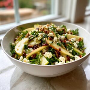 A vibrant bowl of apple feta salad featuring crisp apple slices, crumbled feta cheese, arugula, and chopped nuts.