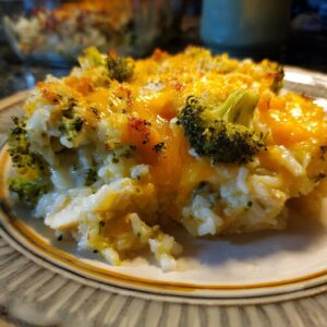 A serving of delicious broccoli rice chicken casserole topped with melted cheddar cheese.
