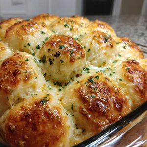 Close-up of golden brown, bubbly buttery cheese garlic rolls baked in a glass dish, sprinkled with parsley.