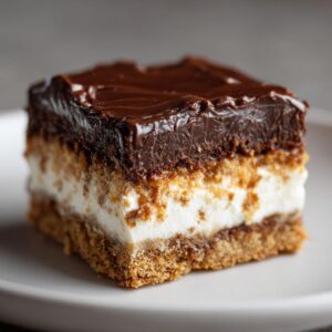 A close-up of a decadent chocolate dream bar, showcasing its rich chocolate topping, creamy filling, and graham cracker crust.