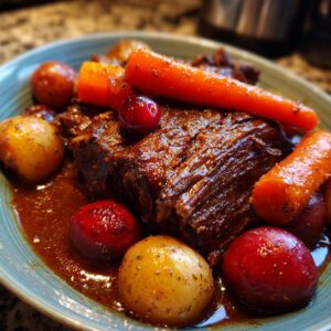 A close-up of a juicy cranberry pot roast served with whole baby potatoes and carrots in a rich gravy.
