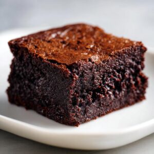 A close-up shot of a single, rich, dark, fudgy sweet potato brownies square on a white plate.
