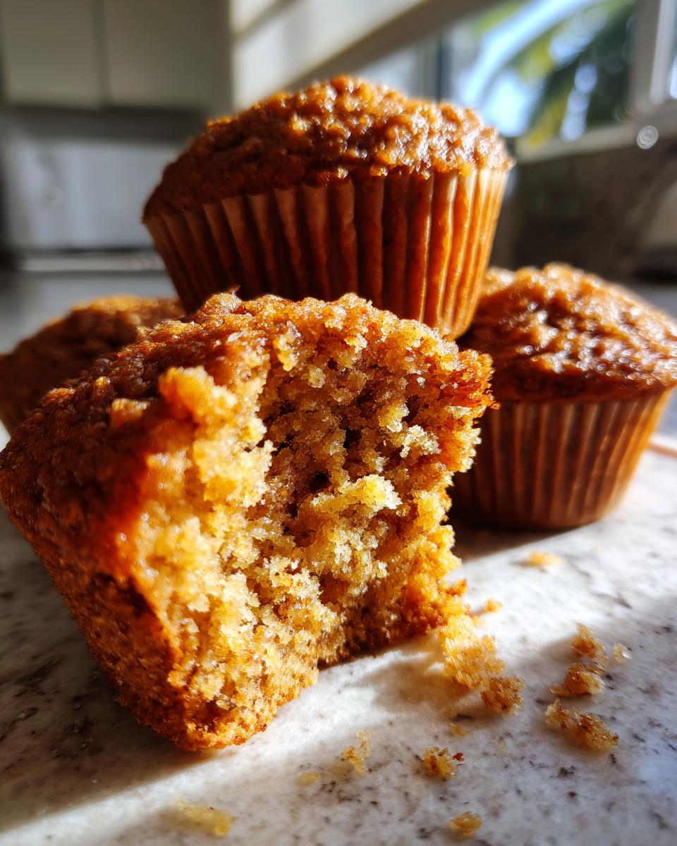 Close-up of a honey bran muffin with a bite taken out, showing its moist texture and crumb.