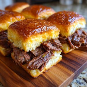 Close-up of juicy Mississippi Pot Roast Sliders on a wooden cutting board, showcasing tender shredded beef and soft buns.