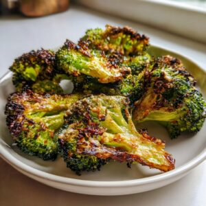 Close-up of crispy, charred, and slightly cheesy smashed broccoli served in a light bowl.