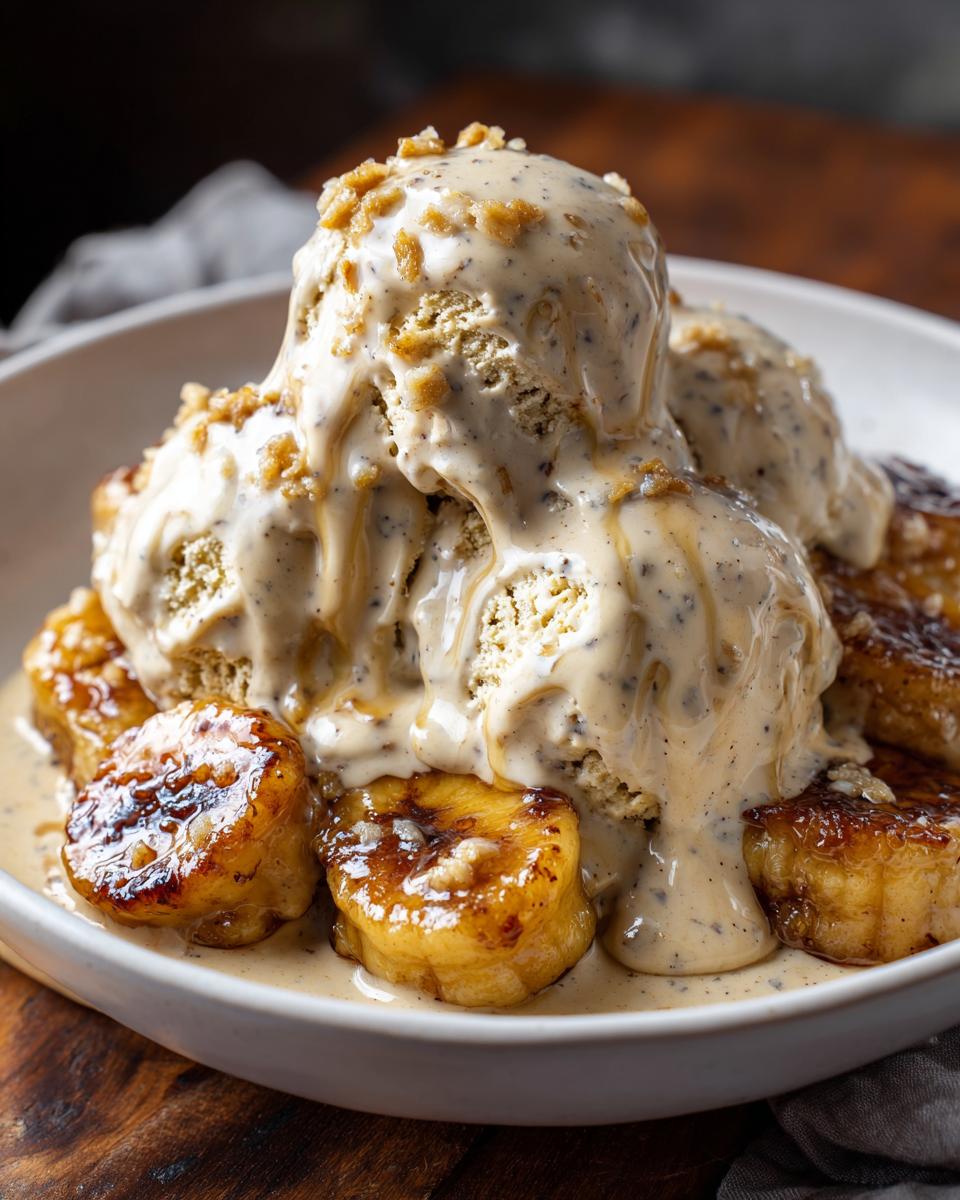 Close-up of caramelized bananas foster topped with melting vanilla bean ice cream and crunchy topping.
