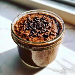 Close-up of rich chocolate overnight oats in a glass jar, topped with mini chocolate chips.