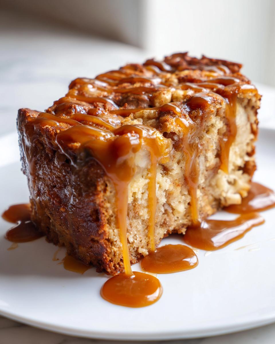 Close-up of a moist slice of apple dapple cake generously drizzled with thick caramel sauce.