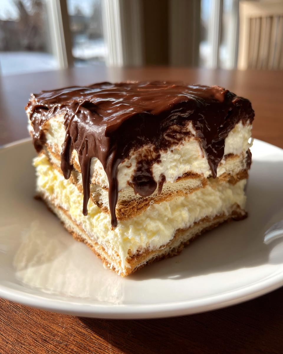 A square slice of no bake eclair cake showing three layers of graham crackers, vanilla pudding, and topped with dripping chocolate ganache.