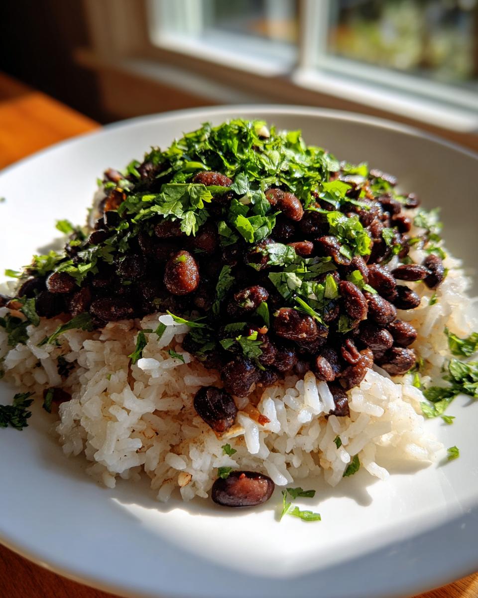 A close-up serving of fluffy white rice topped generously with seasoned black beans and fresh chopped cilantro.