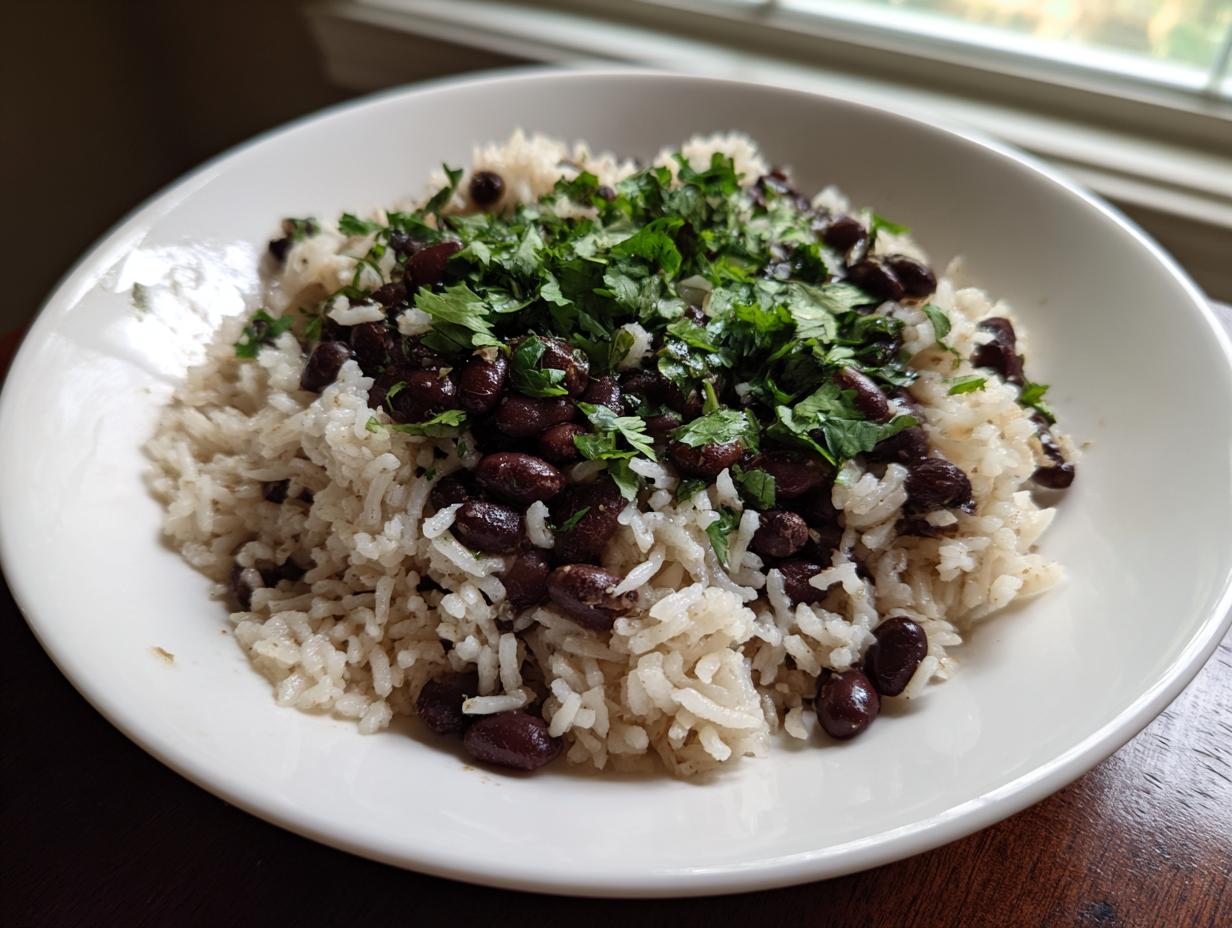 A white bowl filled with fluffy rice topped generously with seasoned black beans and fresh cilantro.