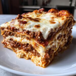 A tall, multi-layered slice of rich meat lasagna with melted, bubbly cheese topping.