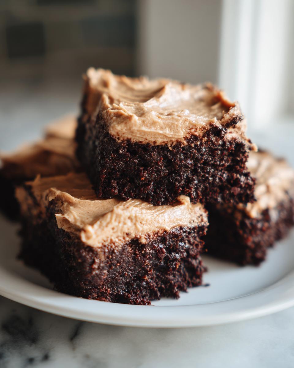Close-up of stacked, fudgy banana bread brownies topped with creamy peanut butter frosting.