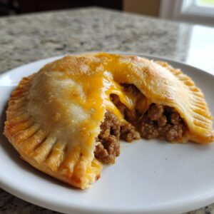 Close-up of a cheesy pocket taco broken open, showing melted cheddar cheese oozing over seasoned ground beef filling.
