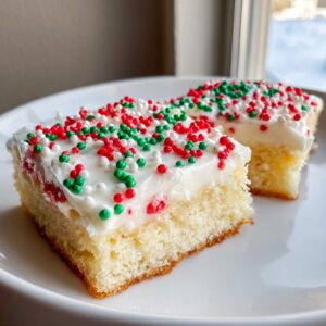 Two squares of light, fluffy christmas sugar cookie bars topped with white frosting and red, green, and white sprinkles.