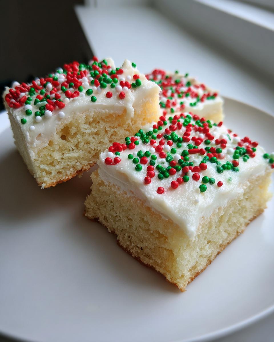 Three squares of christmas sugar cookie bars topped with white frosting and red, green, and white sprinkles.