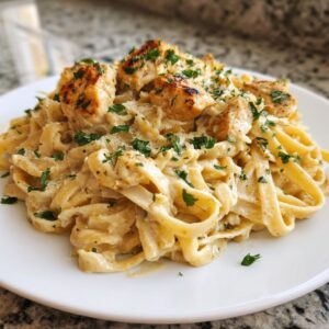 Close-up of creamy chicken pasta featuring fettuccine noodles, grilled chicken pieces, and fresh parsley.