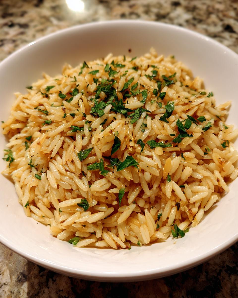 A close-up of fluffy rice pilaf seasoned and topped with fresh chopped parsley in a white bowl.