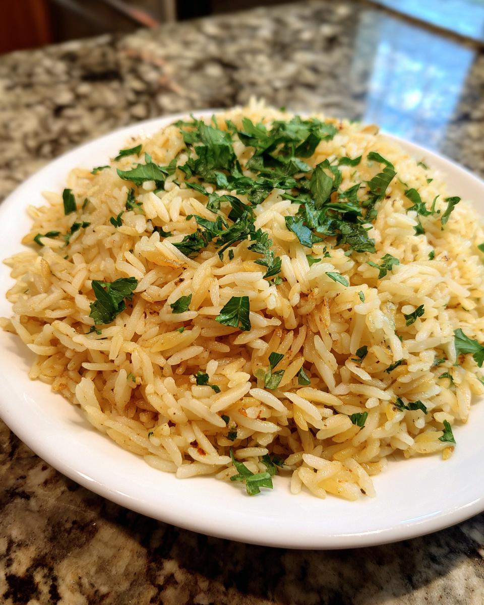 A close-up of fluffy, golden rice pilaf served on a white plate and garnished generously with chopped fresh parsley.