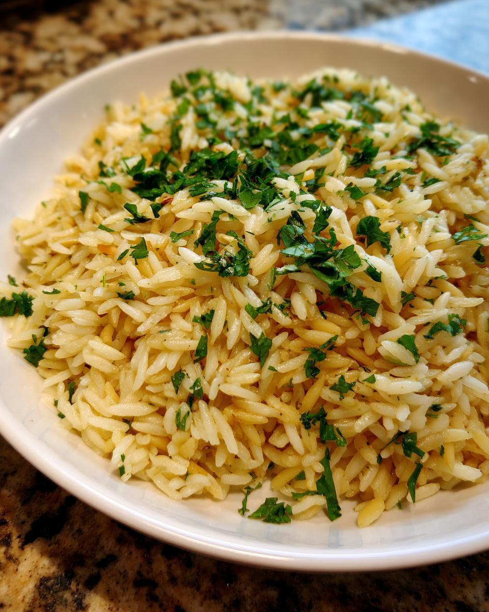 Close-up of fluffy rice pilaf, featuring orzo-like grains garnished generously with chopped fresh parsley.