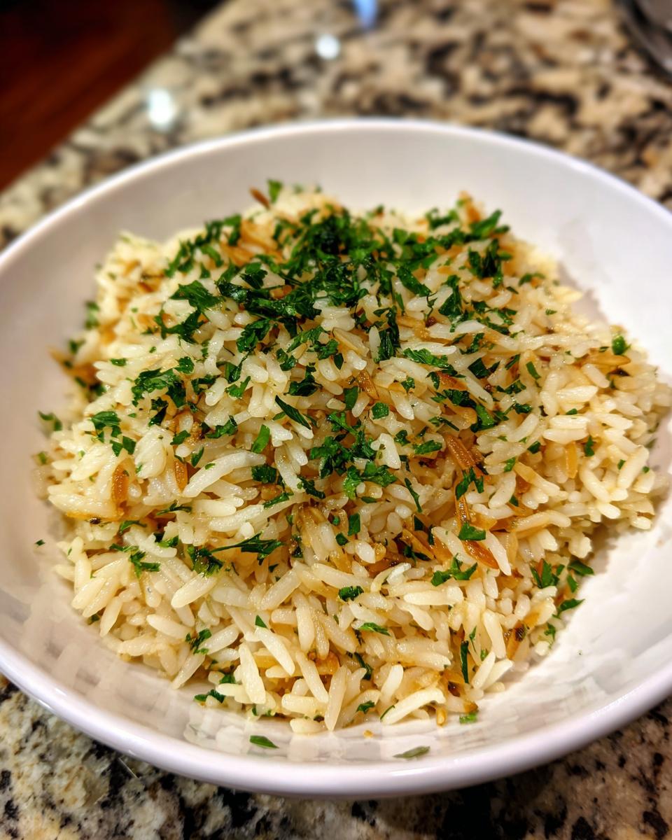 Close-up of fluffy rice pilaf mixed with toasted vermicelli and topped with fresh chopped parsley.
