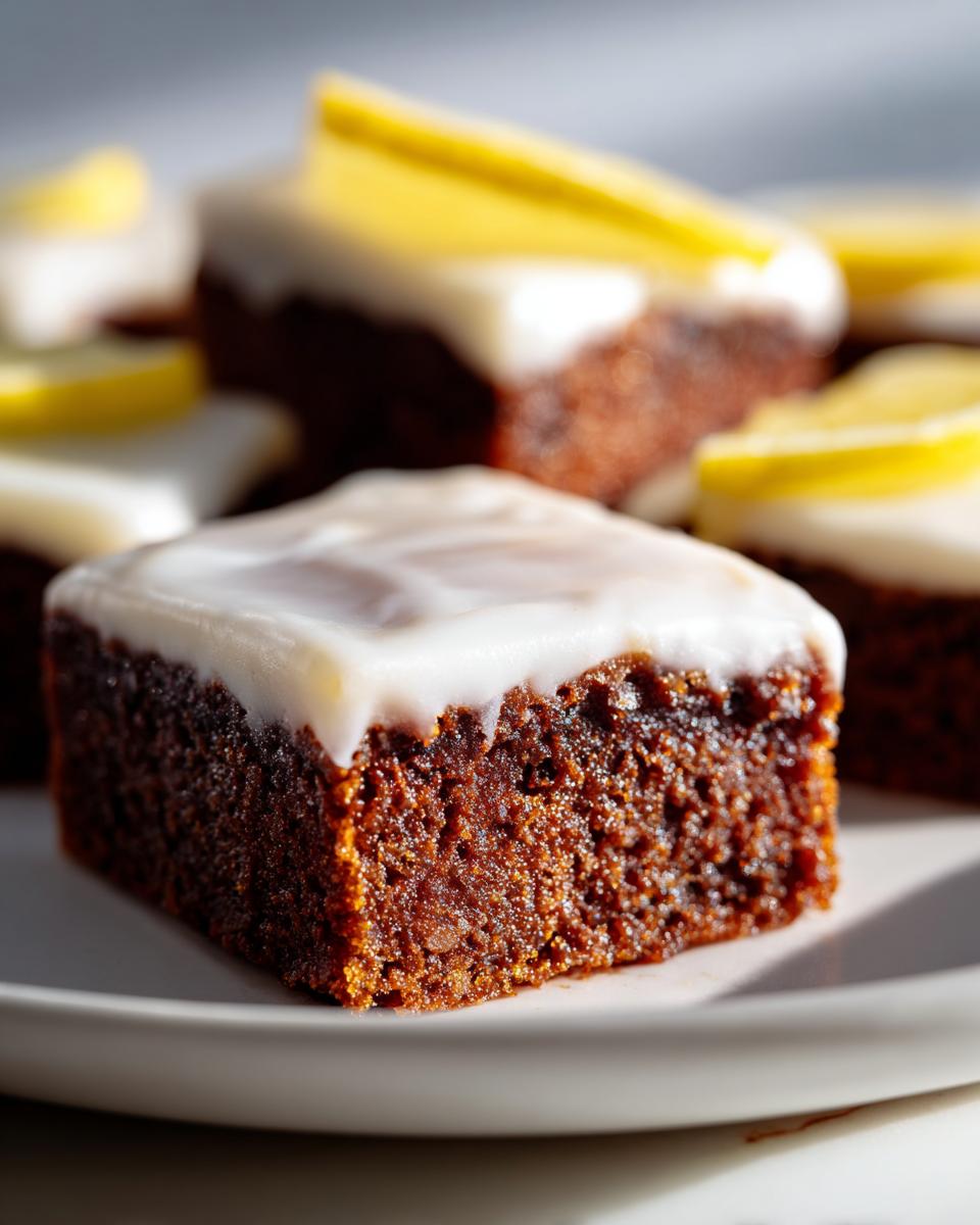 A close-up of a fudgy Lemon Brownies square topped with white glaze and a thin slice of lemon.