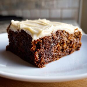 Close-up of a rich, dark slice of banana bread brownies topped with thick cream cheese frosting.