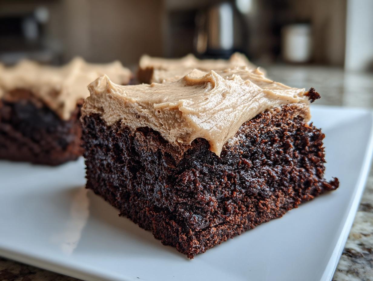 A close-up of a rich, dark chocolate banana bread brownies square topped with thick, light brown frosting.