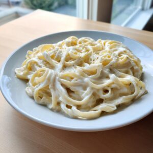 A close-up of fettuccine pasta generously coated in creamy Olive Garden Alfredo sauce and topped with grated cheese.