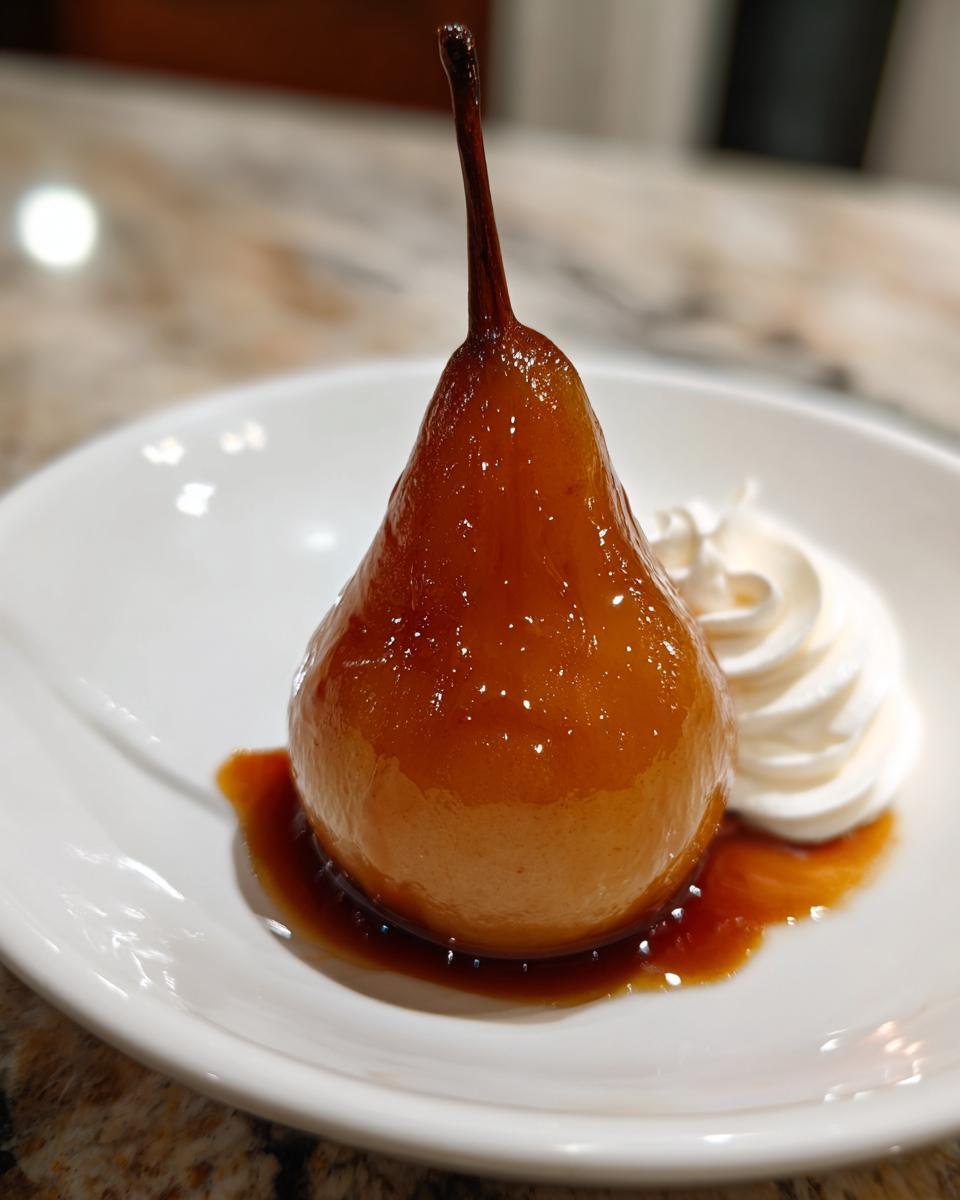 A single, beautifully caramelized poached pear served on a white plate with a dollop of whipped cream.