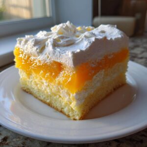 A square slice of Creamsicle Cake featuring layers of yellow cake, bright orange gelatin, and fluffy white whipped topping.