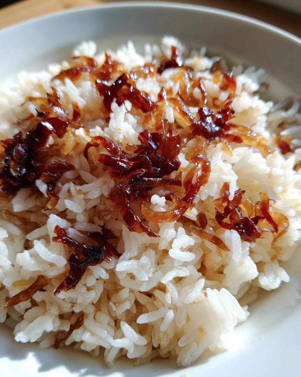 Close-up of fluffy white rice topped with deeply caramelized, crispy fried onions, representing french onion butter rice.