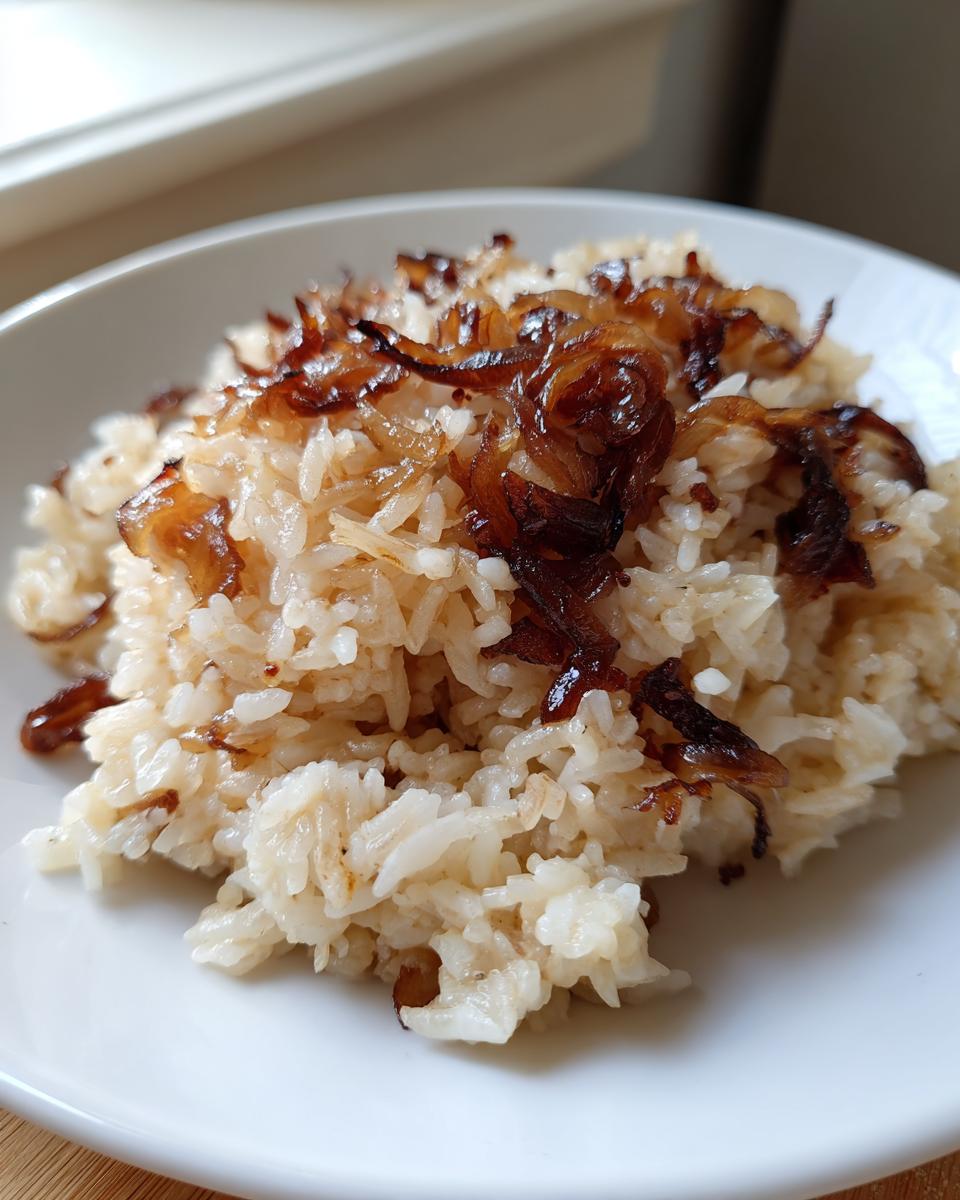 A close-up of fluffy French onion butter rice topped generously with deeply caramelized, crispy fried onions.