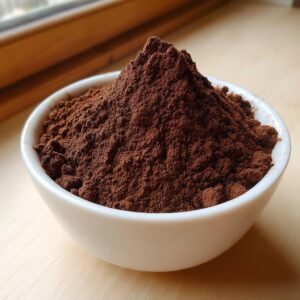 A white bowl filled high with rich, dark brown homemade hot cocoa mix powder.