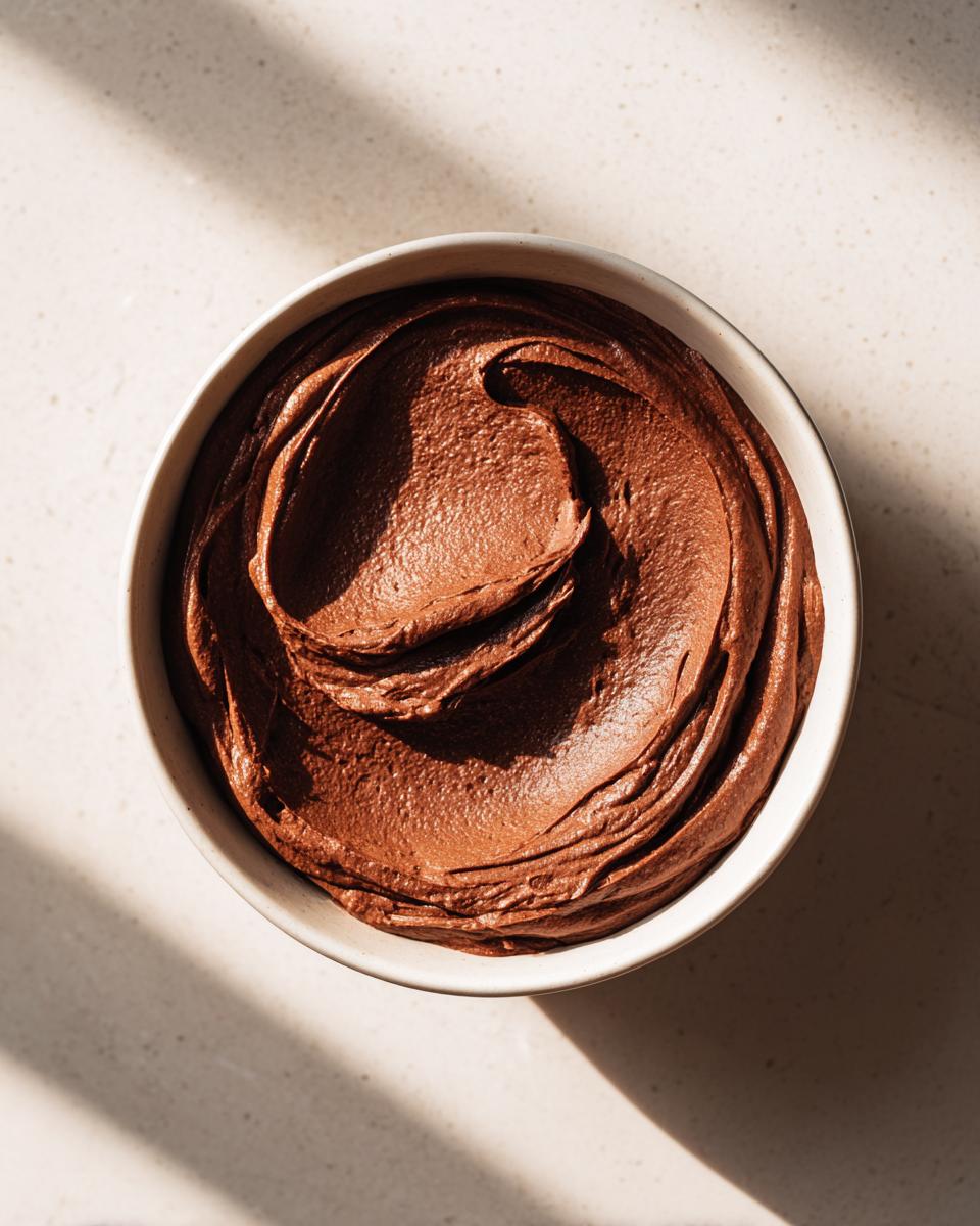 Overhead view of rich, dark chocolate pudding swirled beautifully in a white bowl.